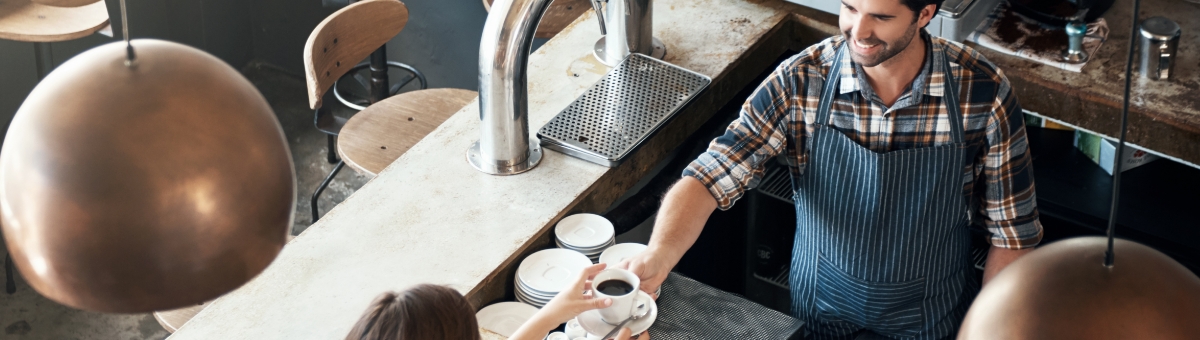 gambar: Seorang staf sedang menyerahkan kopi kepada pelanggan di konter kafe